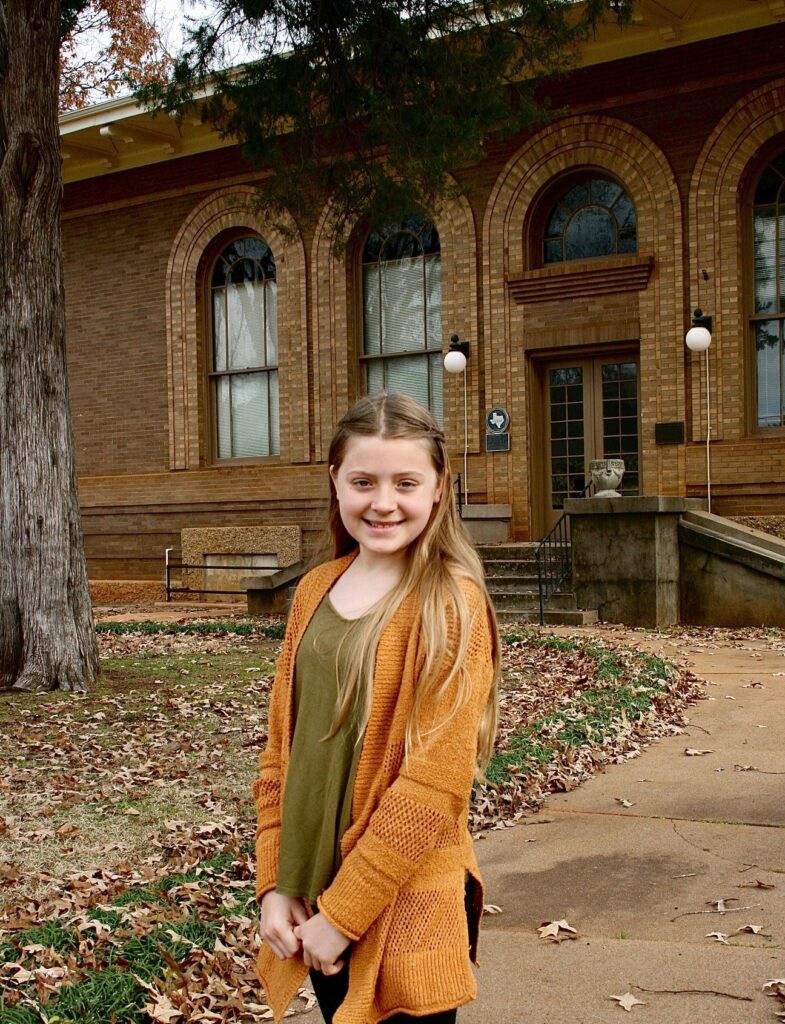 Madeline Moran in front of the Carnegie Library in downtown Palestine Main Street